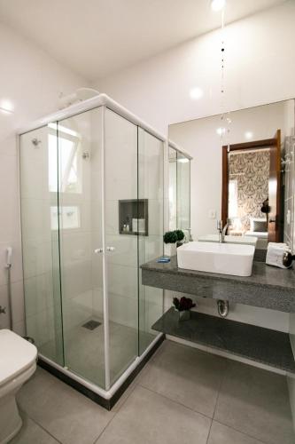 a bathroom with a glass shower and a sink at Pousada do Frei in Búzios