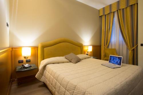 a bedroom with a bed with a laptop on it at Airport Hotel Malpensa in Lonate Pozzolo
