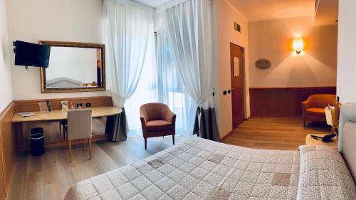 Schlafzimmer mit einem Bett, einem Schreibtisch und einem Spiegel in der Unterkunft Airport Hotel Malpensa in Lonate Pozzolo