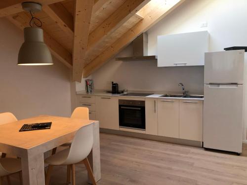 una cucina con tavolo in legno ed elettrodomestici bianchi di Piano C Apartment a Cavalese