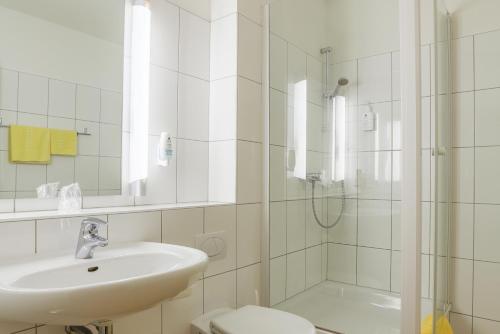 a white bathroom with a sink and a shower at Gästehaus Janzen in Herford