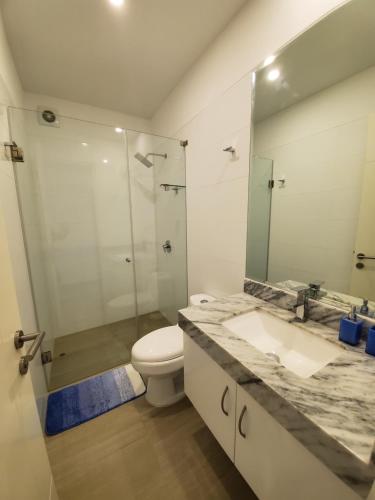 een badkamer met een toilet, een wastafel en een spiegel bij Nuevo Condominio en Ocean Reef in San Bartolo