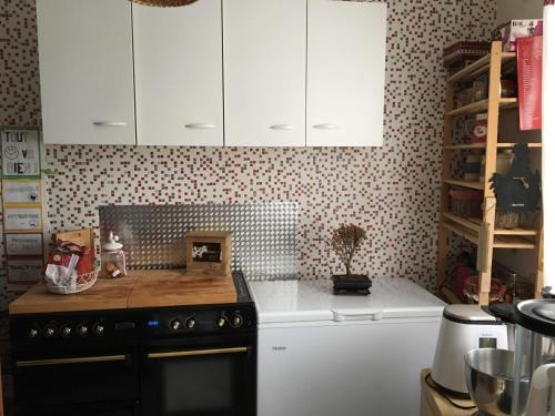 - une cuisine avec des placards blancs et une cuisinière noire dans l'établissement Détente en Normandie, à Damville