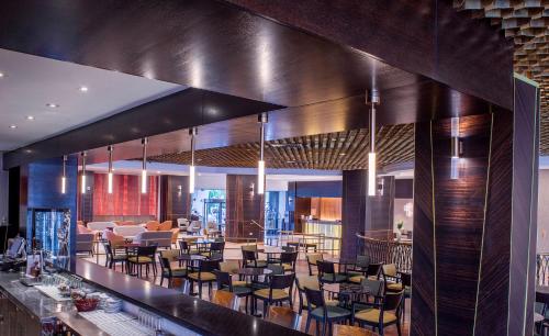 a restaurant with a bar with chairs and tables at Caesar Premier Tiberias Hotel in Tiberias