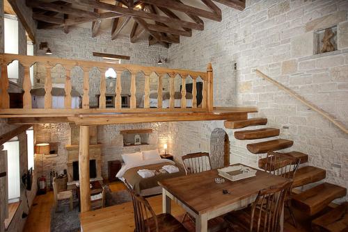 a room with a loft with a wooden table and stairs at Artsistas Houses in Aristi