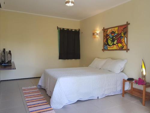 a bedroom with a white bed and a painting on the wall at Pousada Coqueiro Beach in Luis Correia