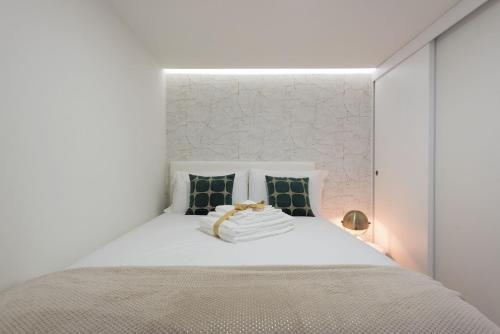 a white bedroom with a white bed with blue pillows at Apartamentos do Prado In Douro in Vila Real