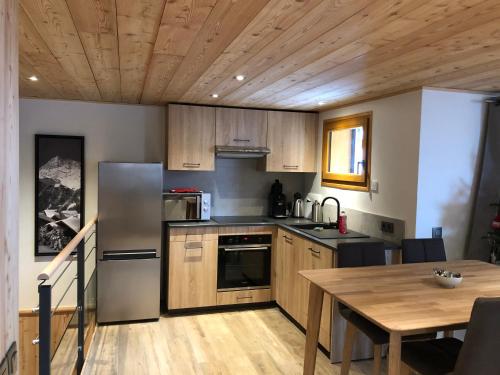 a kitchen with a table and a stainless steel refrigerator at Magnifique Appartement neuf de 60m2 Méribel centre in Les Allues
