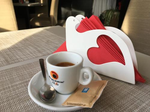 a cup of coffee on a plate next to a bag at Airport Hotel Malpensa in Lonate Pozzolo