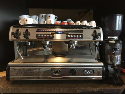 a coffee machine with cups on top of it at Airport Hotel Malpensa in Lonate Pozzolo