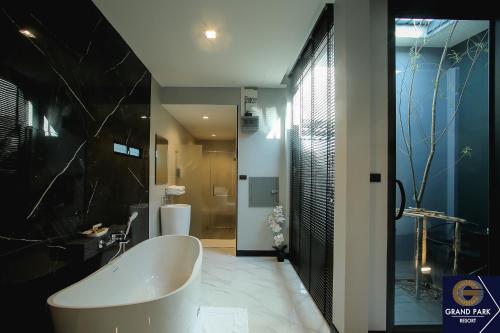 ein Badezimmer mit einer großen Badewanne und einer Dusche in der Unterkunft Grand Park Resort in Ban Chorakhe Bua