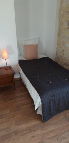 a bedroom with a bed with a black blanket and a lamp at La Maison Des Autres, piscine chauffée, chambres d'hôtes proches Uzès, Nîmes, Pont du Gard in Saint-Géniès-de-Malgoirès