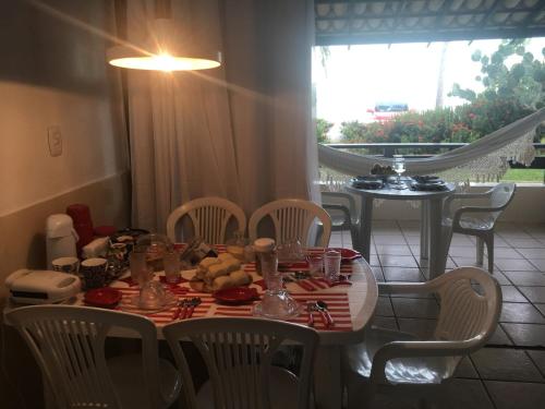 a dining room table with chairs and a table with food on it at Apart-Hotel Beira Mar em Mar Grande in Aratuba Beach