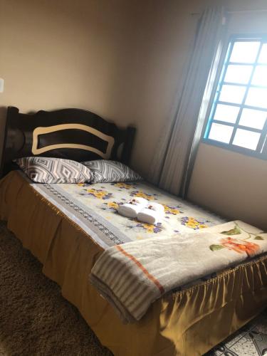 a bed with a quilt on it with a window at Cantinho de Serra in Cunha