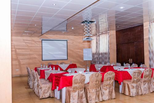 a conference room with tables and chairs and a screen at Kigaliview Hotel and Apartments in Kigali