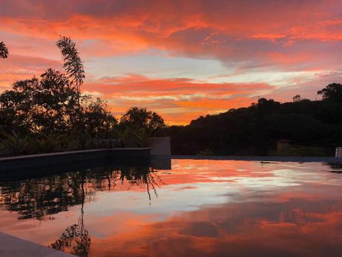 um pôr-do-sol sobre uma piscina com o céu em Pousada Villa Canaã em Búzios