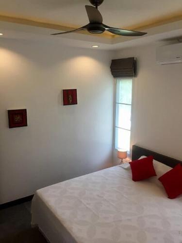 a bedroom with a bed with a ceiling fan at Pearl Villa in Nathon