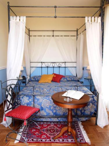 a bedroom with a canopy bed with a table and a table sidx sidx at Petit Chateau in Montecatini Terme