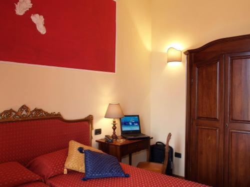 a bedroom with a bed and a desk with a laptop at Petit Chateau in Montecatini Terme