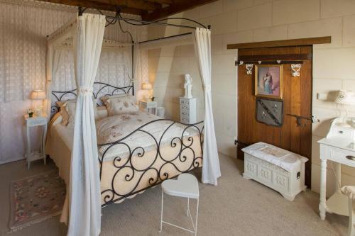 a bedroom with a canopy bed and a chair at Les charmes in Valençay