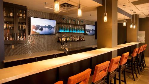 a bar in a restaurant with orange chairs at Holiday Inn & Suites Mississauga West - Meadowvale by IHG in Mississauga