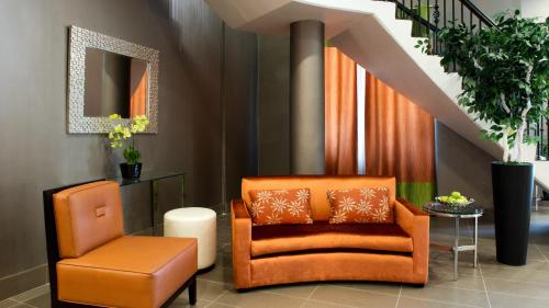 a living room with an orange chair and a stool at Holiday Inn & Suites Mississauga West - Meadowvale by IHG in Mississauga