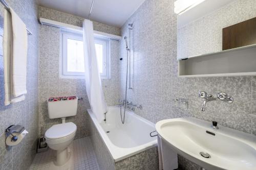 uma casa de banho com um WC, um lavatório e uma banheira em Via Sulten 12 em Flims
