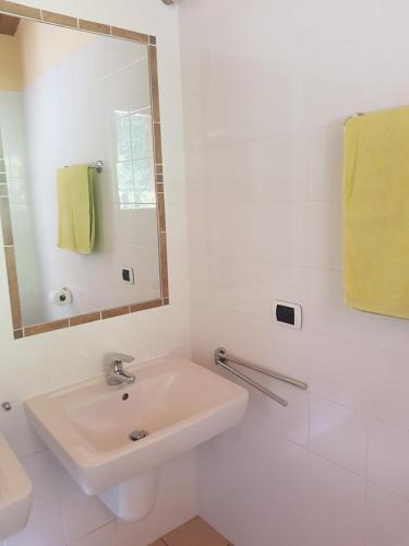 een witte badkamer met een wastafel en een spiegel bij Villa Sara - Seeblick - Sea view in Argegno