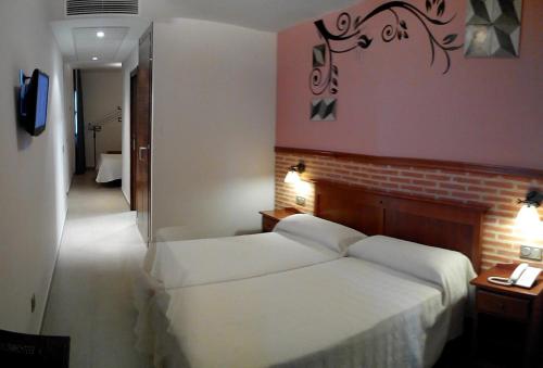 a bedroom with a white bed and a brick wall at Hotel Ecologico Toral in Santa Cruz de Mudela