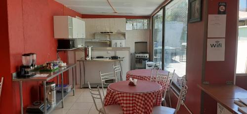 una cocina con paredes rojas, mesas y sillas en Hostal Estadio Nacional, en Santiago