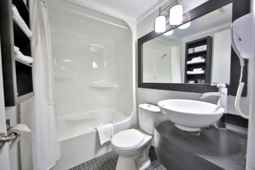 a bathroom with a sink and a toilet and a mirror at Motel Newstar Laval in Laval