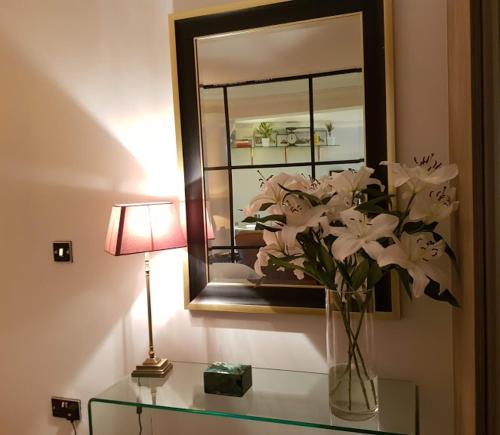 a vase of white flowers on a glass table with a lamp at Cocoa Isabella - River fronted with secure parking in York