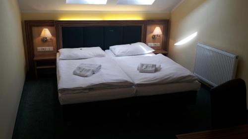 a bedroom with a large bed with two towels on it at CORNER HOTEL U DIVADLA*** - ZNOJMO in Znojmo