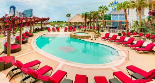 a swimming pool with red lounge chairs and a resort at Margaritaville Resort Casino in Bossier City