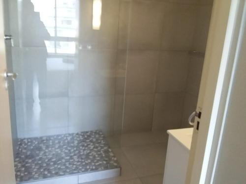 uma casa de banho com um chuveiro e uma porta de vidro em Sunset 786 Holiday Accom-212 em Strand