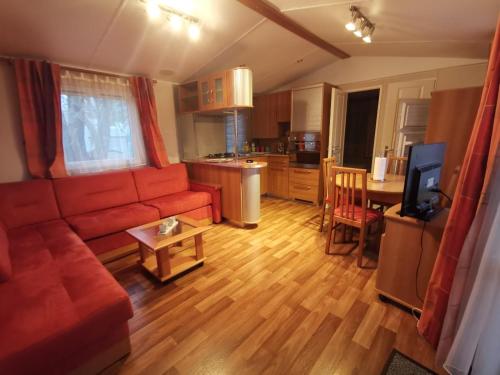 a living room with a red couch and a kitchen at Pyla Chalet et mobilhom 6 personnes Magda in La Teste-de-Buch