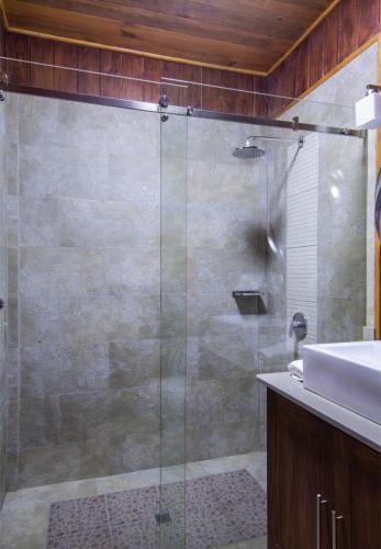 a glass shower in a bathroom with a sink at Lucero Golf and Country Club Tree Houses in Boquete