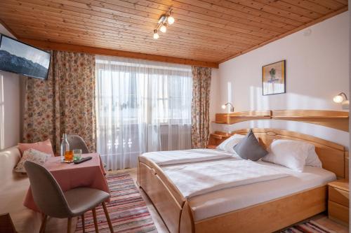 een slaapkamer met een bed, een tafel en een stoel bij Welzenhof in Walchsee