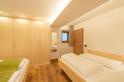 a bedroom with two beds and wooden cabinets at Piz da Cir in Colfosco