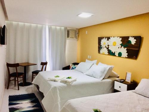 um quarto de hotel com duas camas e uma mesa em Pousada Costão do Sol em Angra dos Reis
