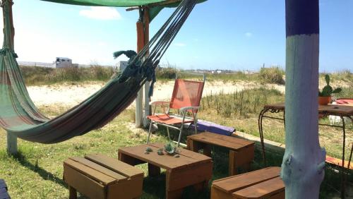 a hammock and a chair and a table in a field at cabopolonioalojamiento in Cabo Polonio