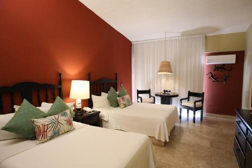 Habitación de hotel con 2 camas, mesa y sillas en Hotel Montetaxco en Taxco de Alarcón
