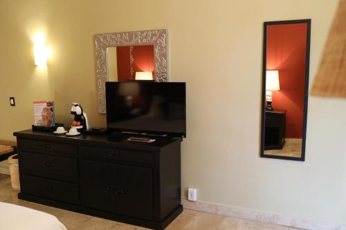 a room with a television on a dresser with a mirror at Hotel Montetaxco in Taxco de Alarcón