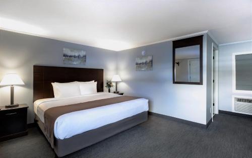 a hotel room with a large bed and a mirror at Mt. Madison Inn & Suites in Gorham