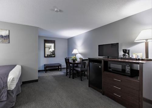 a hotel room with a bed and a desk with a microwave at Mt. Madison Inn & Suites in Gorham