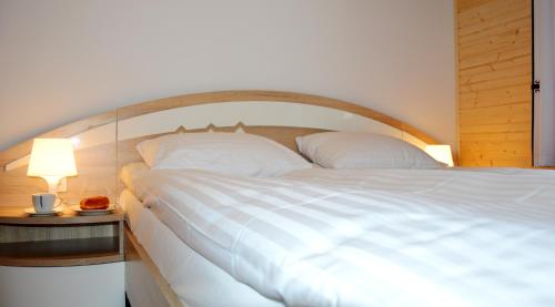 a bedroom with a large white bed and a side table at Przystań Góralska in Szczawnica