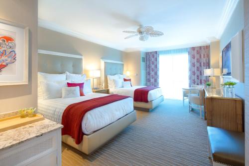 a hotel room with two beds and a desk at Margaritaville Resort Casino in Bossier City