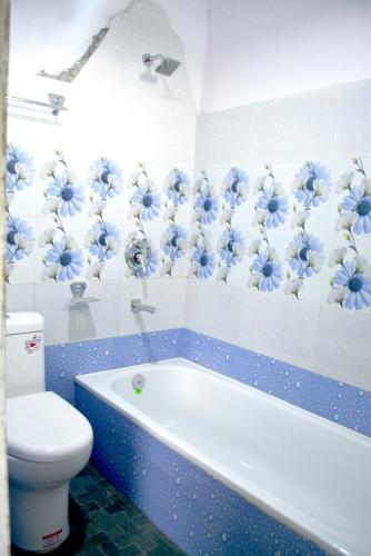a bathroom with a toilet and a tub with blue flowers on the wall at Hotel Rupee Pvt. Ltd. in Pokhara