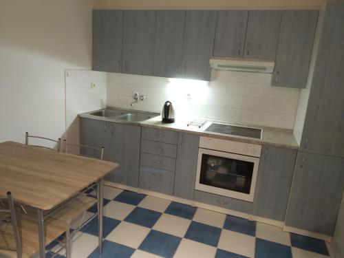 cocina con armarios grises, fregadero y mesa en Apartmány Pod strání en Vrchlabí