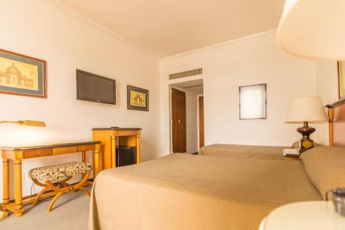 a bedroom with a bed and a desk and a tv at Hotel Libertador in Tandil